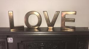 Freestanding capital letters made from shiny metal spelling the word "LOVE" 