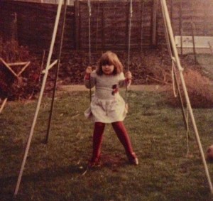 Lucy, aged 5, seated on her swing on the lawn in her garden. 