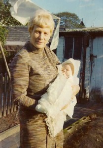 Jolen's grandmother standing in a sunny garden holding baby Jolene dressed in Christening finery