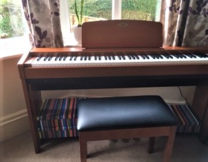 Margaret's electric piano in the window with a view of the hedge in the garden in the background