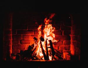 A roaring fire lighting up the brick fireplace behind it with a warm red glow