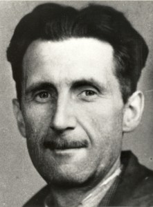 A photograph of George Orwell's face looking directly into the camera, taken from his National Union of Journalists membership card