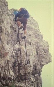 Margaret is coming backwards down a  metal ladder on a vertical rock face. 