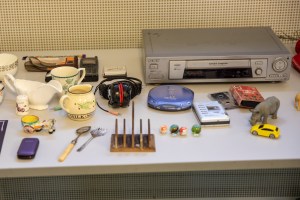 A table containing toys, a radio, a walkman for cassette tapes, a  portable CD player, mobile phone and several kitchen items