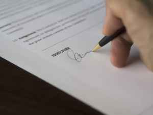 A photo of a hand signing a signature at the end of a questionnaire.