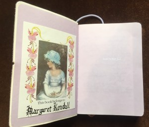 The book plate, which features a painting of a Victorian girl in a frilly dress and mop cap, holding a bunch of flowers. There is a border of fuchsia flowers.  Under the painting are the words This book belongs to.. and Margaret Kendall written in fancy writing.