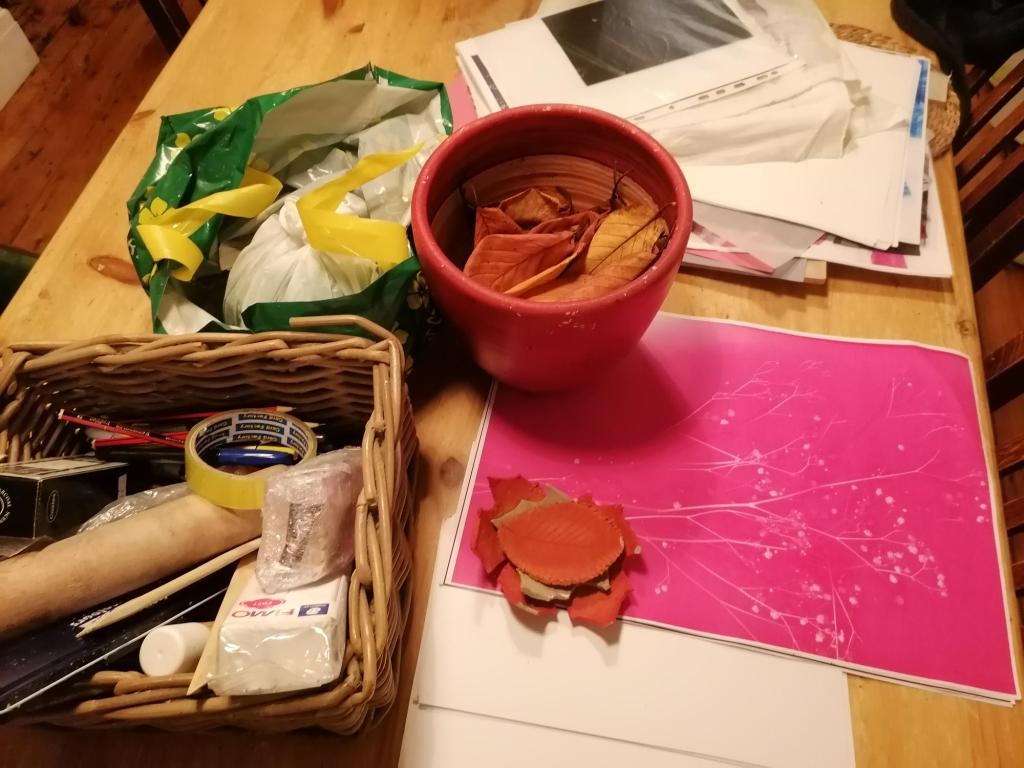 A close up of baskets of clay, coloured paper and a bowl full of autumn leaves on one of the tables. 