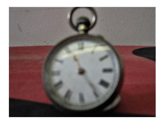 The watch face, with Roman numerals and a silver surround, with a fob at the top. 