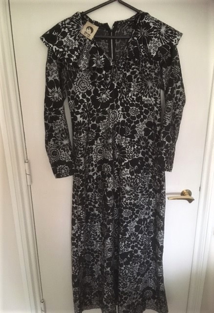 Jean's party dress.  It is covered with large black flowers on a white background, with a v-shaped neckline, caped shoulders and long sleeves.