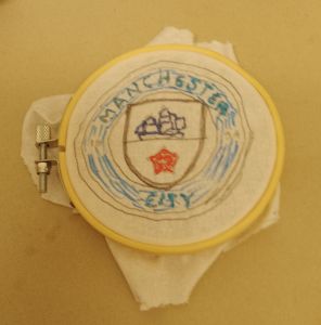 The words Manchester City are embroidered in the correct shade of blue for the football team's badge, circling the shield which contains a sailing ship and the red rose symbolising Lancashire.  